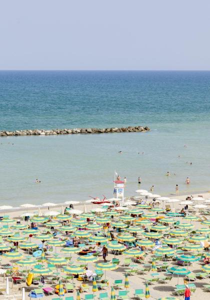 Crowded beach with colorful umbrellas and calm sea.