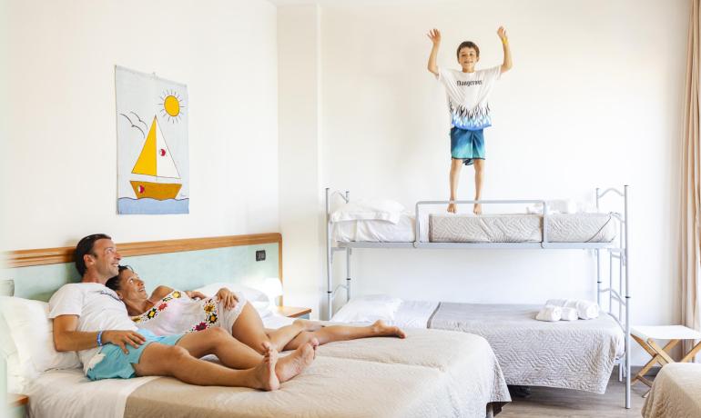 Famiglia in vacanza, bambino che salta sul letto a castello.