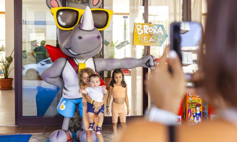 Enfants posent avec un rhinocéros géant devant Brora Beach.