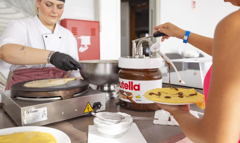 Chef prepara crêpe con Nutella, cliente aggiunge cioccolato.